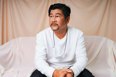 Fashion portrait of cool old elderly senior man in white shirt sitting on a couch.の写真素材