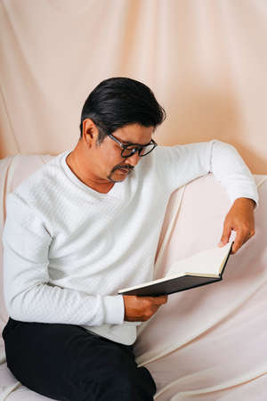 Portrait of hipster old elderly senior man wearing eyeglasses reading a book.の写真素材