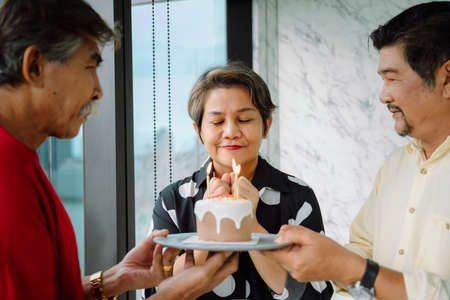 Old elderly senior people celebrate birthday party with cake to old woman.の写真素材