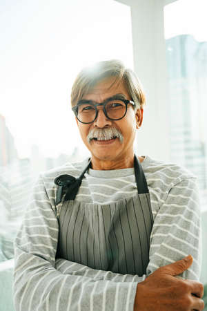 Portrait of old elderly senior waiter with eyeglasses in restaurant.