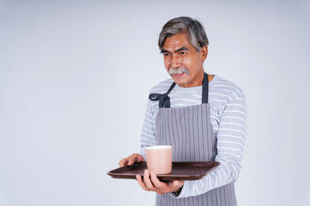 Portrait of old elderly senior waiter holding coffee cup and tray isolate on white background.の写真素材
