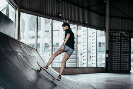 Woman in shorts jeans riding the longboard at rusty curve over and over in her free time.の写真素材