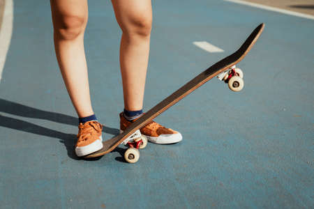 Cropped image of woman's legs while playing longboard on the blue part with one side down and one side up.の写真素材
