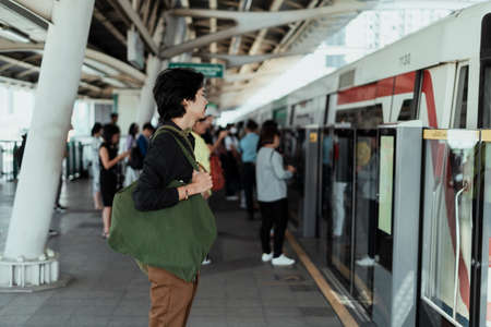 Black hair guy standing calmly at the skytrain station while other people try to get inside the train.の写真素材
