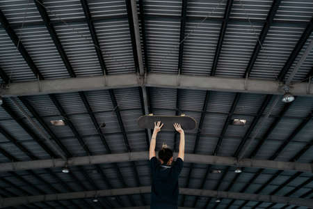 Dark blue polo shirt woman standing and raise the longboard over her head.の写真素材
