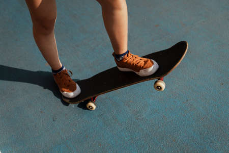 Cropped image of woman's legs while playing longboard on the blue part with one side down and one side up.の写真素材