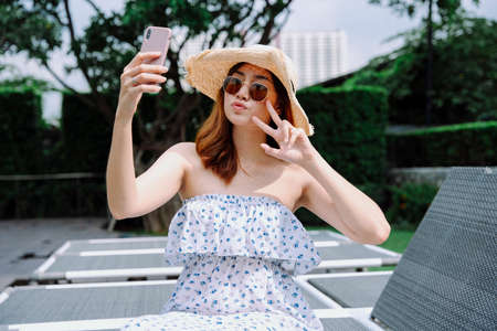 Beautiful asian woman traveler wear hat and sunglasses taking selfie with smartphone.の写真素材
