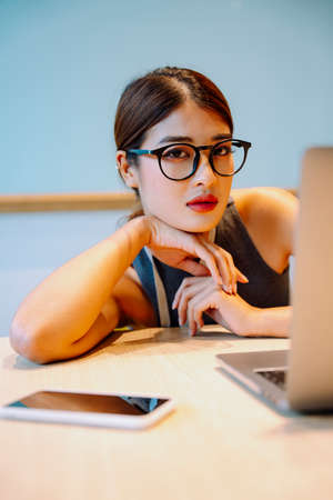 Asian business woman wear eyeglasses sitting infront of computer laptop.の写真素材