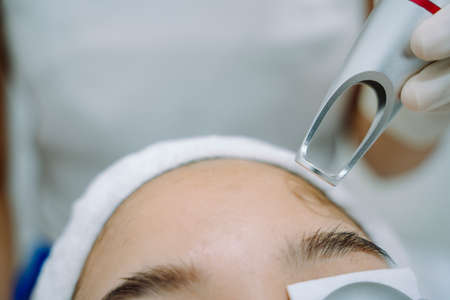Asian woman getting laser and ultrasound face treatment in medical spa center.の写真素材
