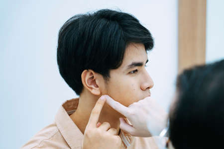 Beautician checking young man face for facial treatment in beauty clinic.の写真素材