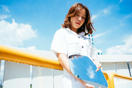 Young asian thai woman holding mirror outdoors in city.