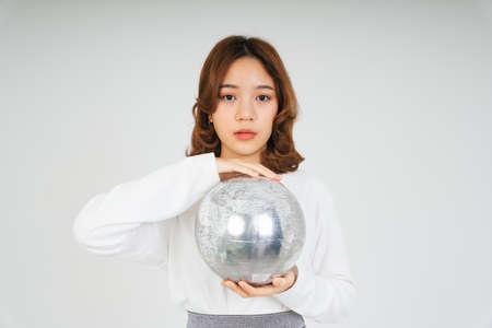 Young asian woman with silver globe ball isolate on white background.の写真素材