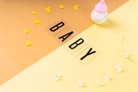 Baby word with milk bottle on light yellow and orange background.の写真素材