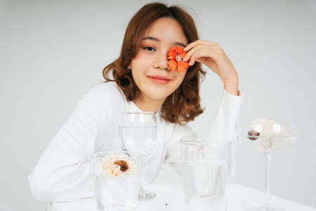 Fashion portrait of young asian woman hold red flower with water glasses isolate on white...