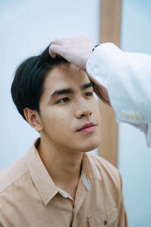 Beautician checking young man face for facial treatment in beauty clinic.の写真素材