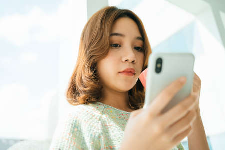 Asian woman chat on smartphone and drink coffee at home.