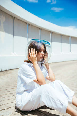 Asian woman wearing glass bowl like astronaut to protect herself from pollution on earth.