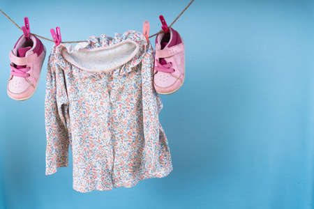Kid shirt and shoes hanging on a rack after laundry on blue background.の写真素材