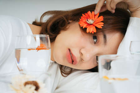 Fashion portrait of young asian woman hold red flower with water glasses isolate on white...