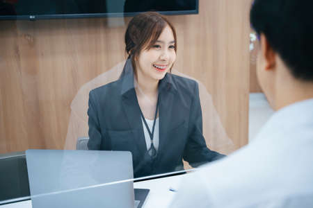 Beautiful asian receptionist giving information to customer behind the desk.
