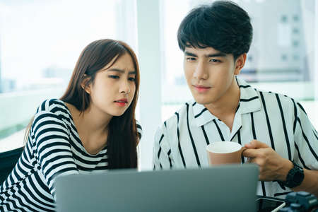 Two asian influencers doing live video streaming with computer laptop together.の写真素材