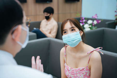 Young asian woman wear mask talking to doctor in hospital.の写真素材