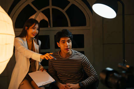 Asian influencer and MC doing interview for TV show at studio indoors.