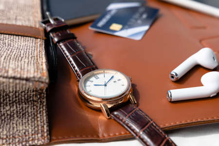 Vintage wrist watch and wireless earphone on modern desk.