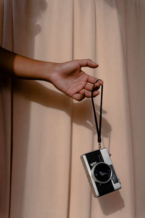 Hand holding vintage camera isolated on beige background.の写真素材