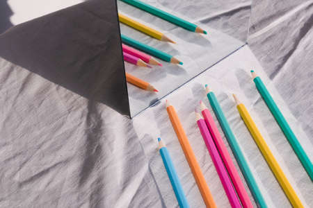 Colourful pencil in a row reflection in mirror on table.の写真素材