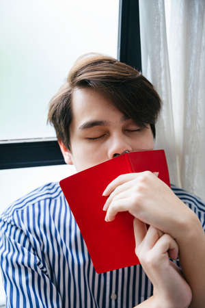 Tired asian young student fall asleep while reading a book.の写真素材