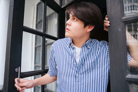 Asian young man open the window in the morning.