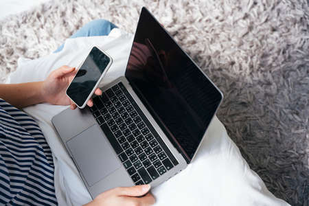 Business man working with laptop and smartphone on white pillow. Work from home concept.