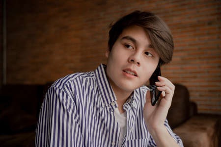 Close up portrait - Asian young man talking on the phone at home.