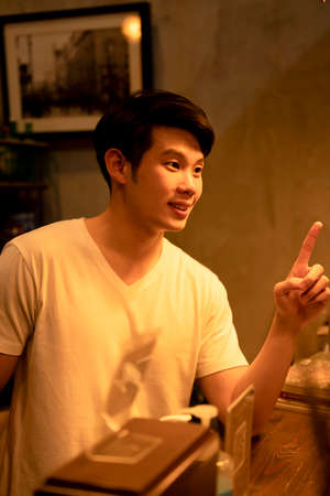 Asian young man ordering food and beverage at counter bar.