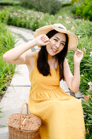 Portrait of beautiful asian woman in yellow dress pick up flower in country side farm.の写真素材