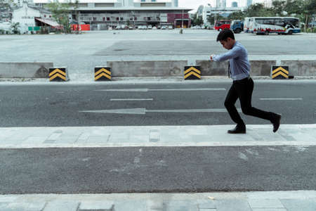 Businessman looking at his watch and running.