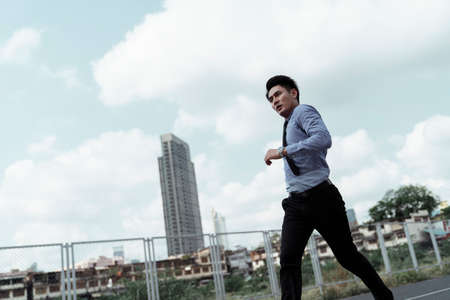 Businessman running on urban street in daylight.