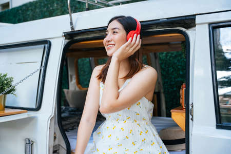 Beautiful asian woman in white dress listen to music with wireless headphone in CV car.の写真素材
