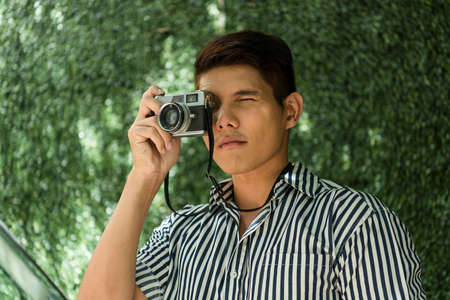 Portrait of beginner asian photographer try to use vintage film camera at park.