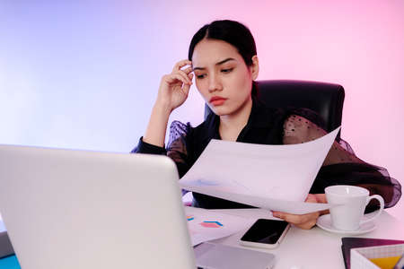 Asian businesswoman black hair reading document paper in office.
