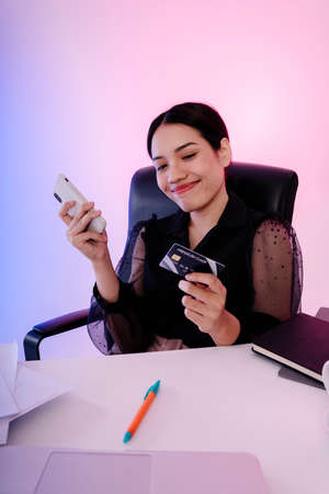 Asian businesswoman buying stuff from online platform with smartphone and credit card.の写真素材