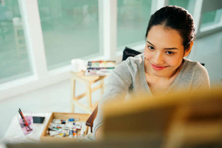 Portrait of young asian artist woman painting on canvas in studio.の写真素材