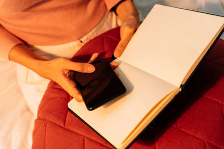 Top view - woman using smartphone and reading a book in warm light.の写真素材