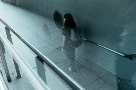 Asian thai backpacker woman walking on stair into underground metro.