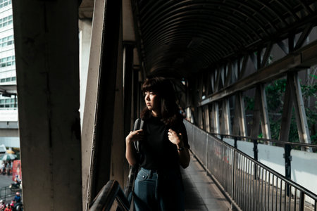 Asian thai backpacker woman walking on overpass looking at the road in Bangkok city.の写真素材