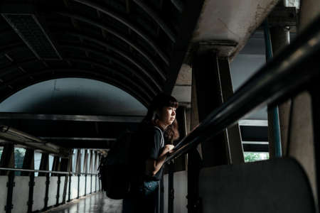 Asian thai backpacker woman looking at the road, standing on overpass.