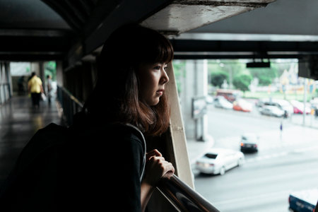 Asian thai backpacker woman looking at the road, standing on overpass.の写真素材