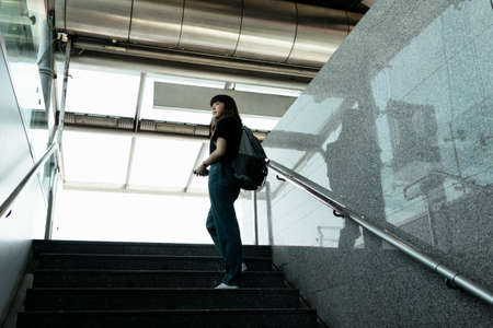 Asian thai backpacker woman walking on the stair at metro station.