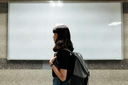 Sideview of Asian thai backpacker woman over white board background.